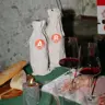 Twee anonieme flessen wijn in stoffen zakjes met de letters A en B, naast twee glazen rode wijn