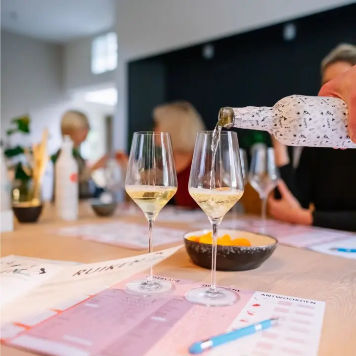Witte wijn wordt ingeschonken uit een anonieme fles aan een tafel met proefformulieren