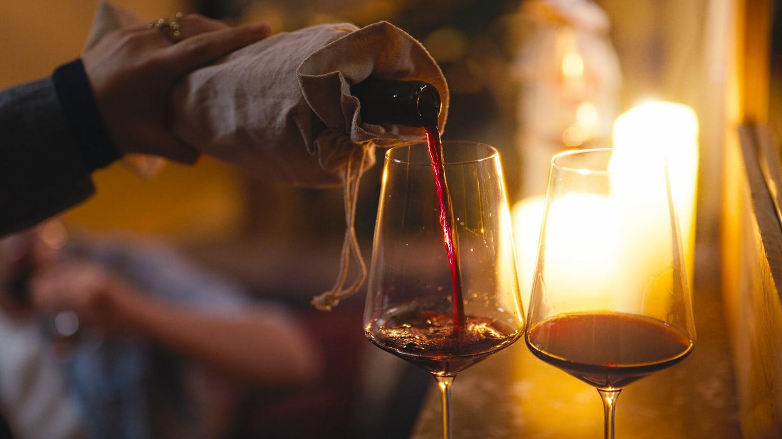 Wijn wordt blind ingeschonken uit een fles in een stoffen zakje
